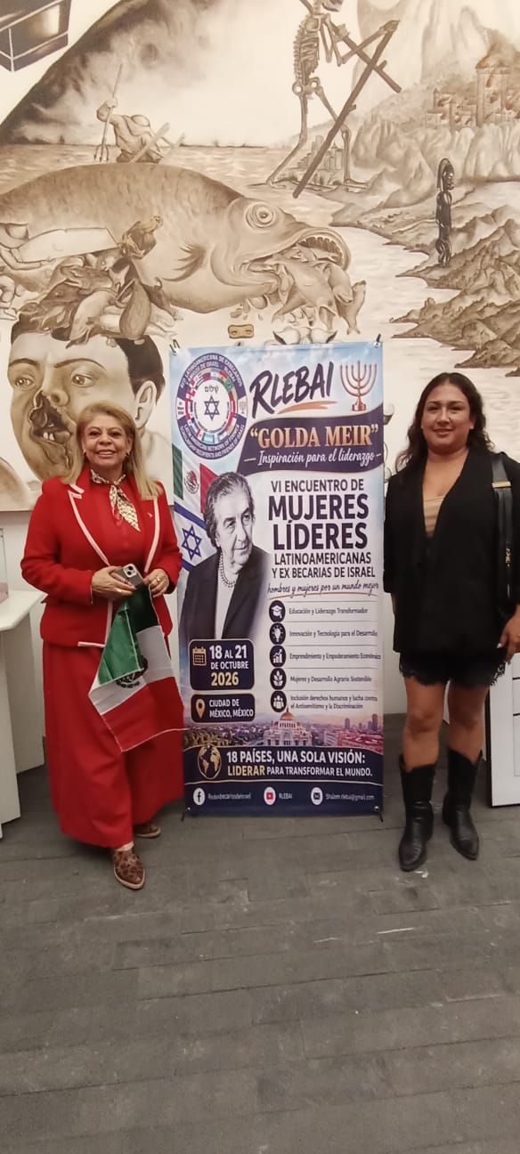 Dos participantes junto al cartel del VI Encuentro Golda Meir.